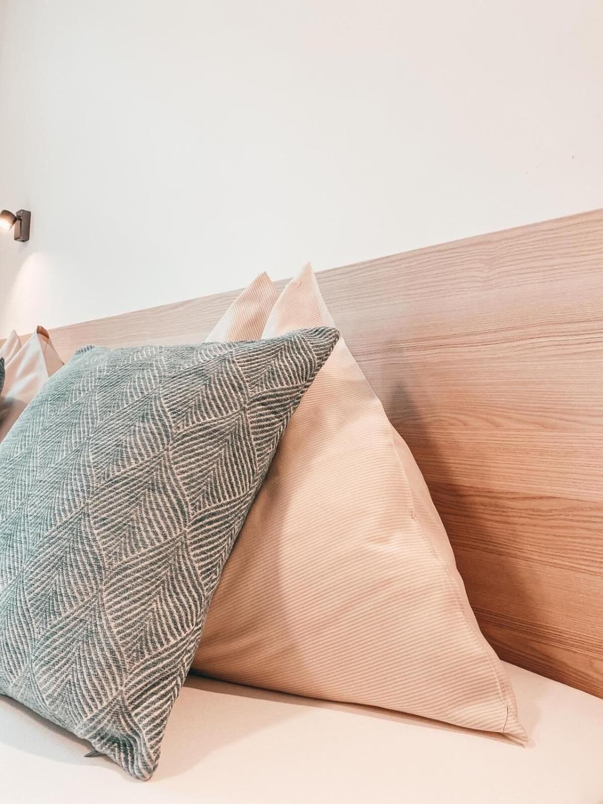 A bed with two pillows and a wooden headboard.
