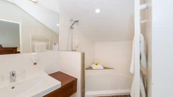 A bathroom with a sink, mirror, shower, and bathtub.