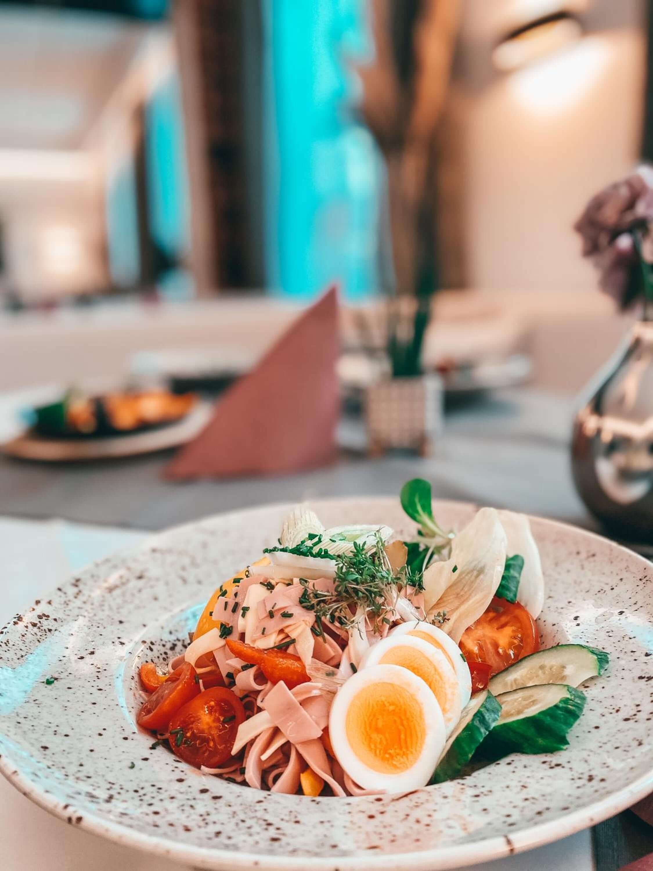 A plate of food with various ingredients including sliced vegetables, meat, and eggs.