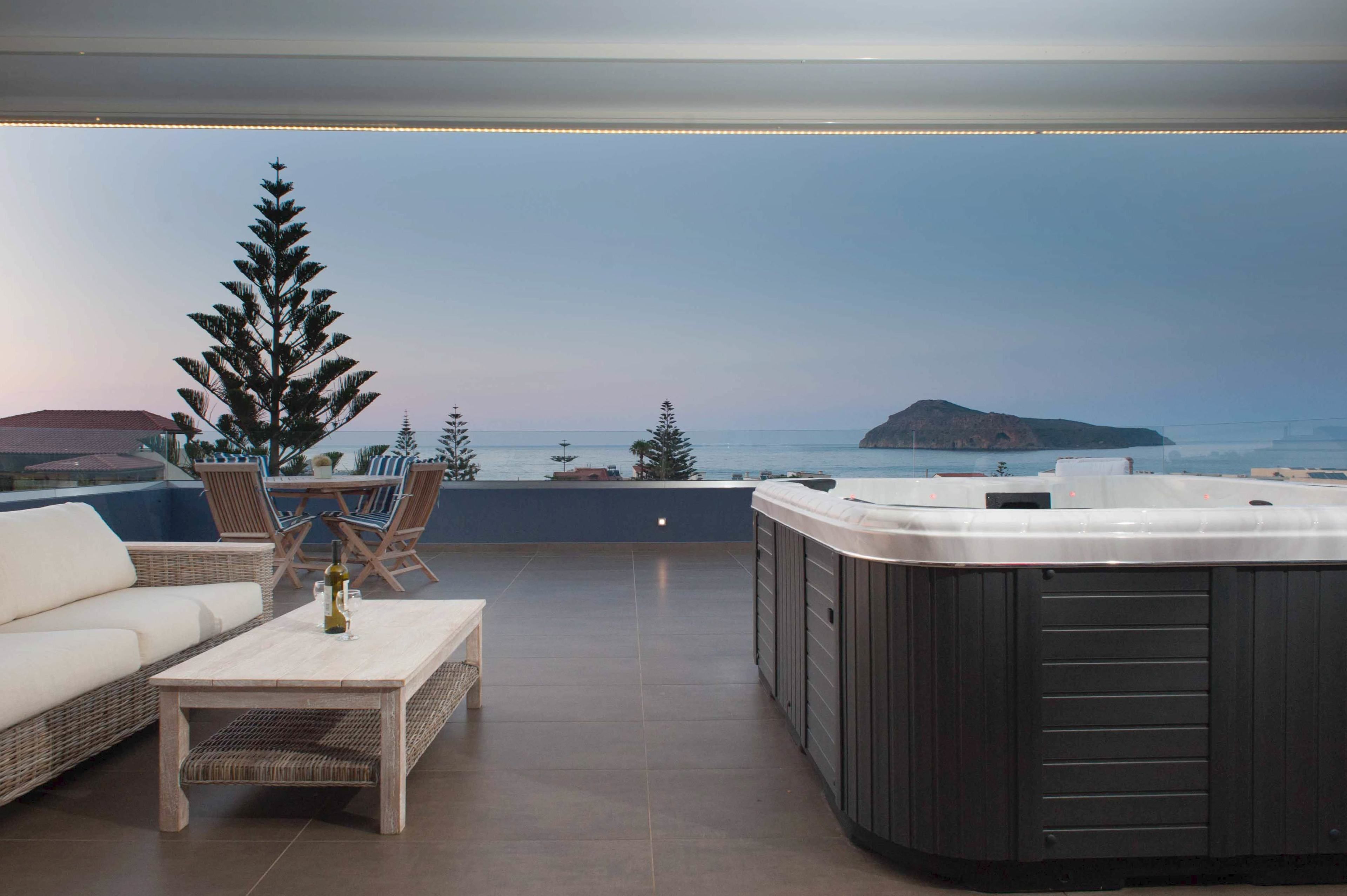 A rooftop terrace with a hot tub, seating area, and a view of the sea.