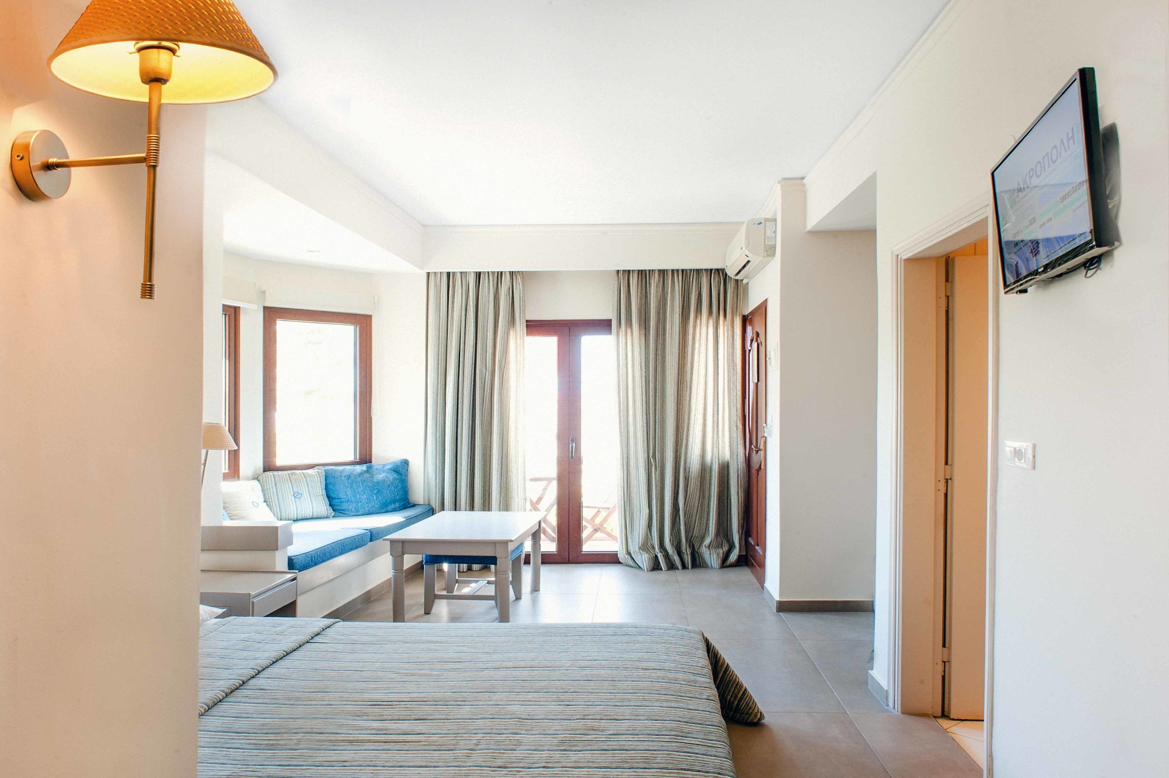 A hotel room with a bed, a sofa, a table, and a TV.