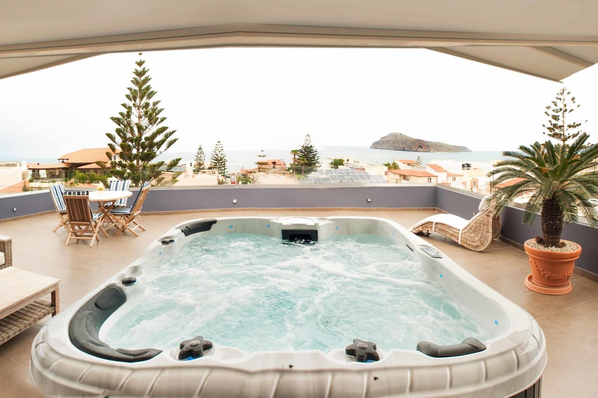 A hot tub on a balcony with a view of the sea and a small island.
