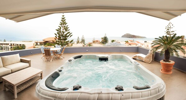 A hot tub on a balcony with a view of the sea and a small island.