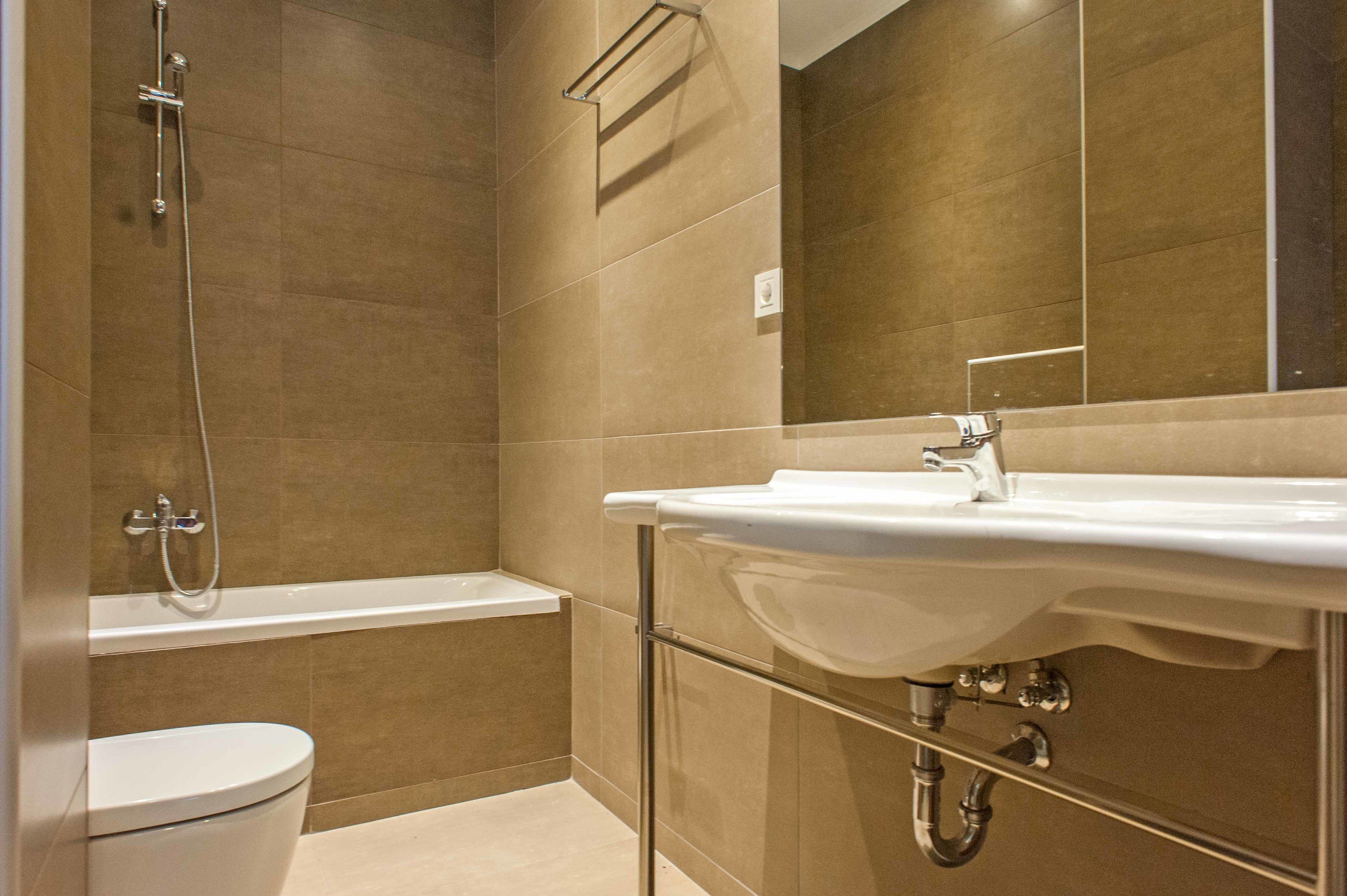 A modern bathroom with a bathtub, toilet, and sink.
