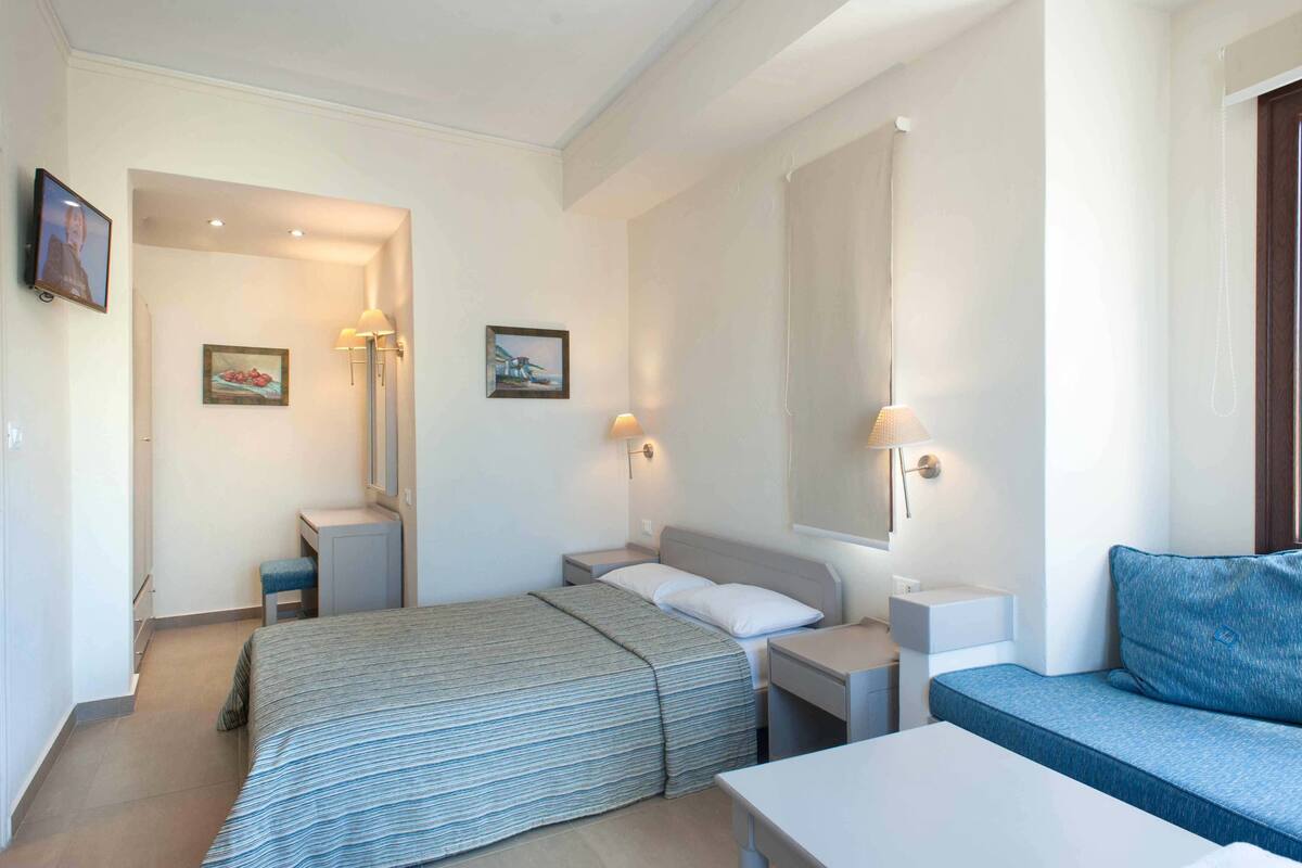 A modern bedroom with a bed, bedside tables, a desk, and a sofa.