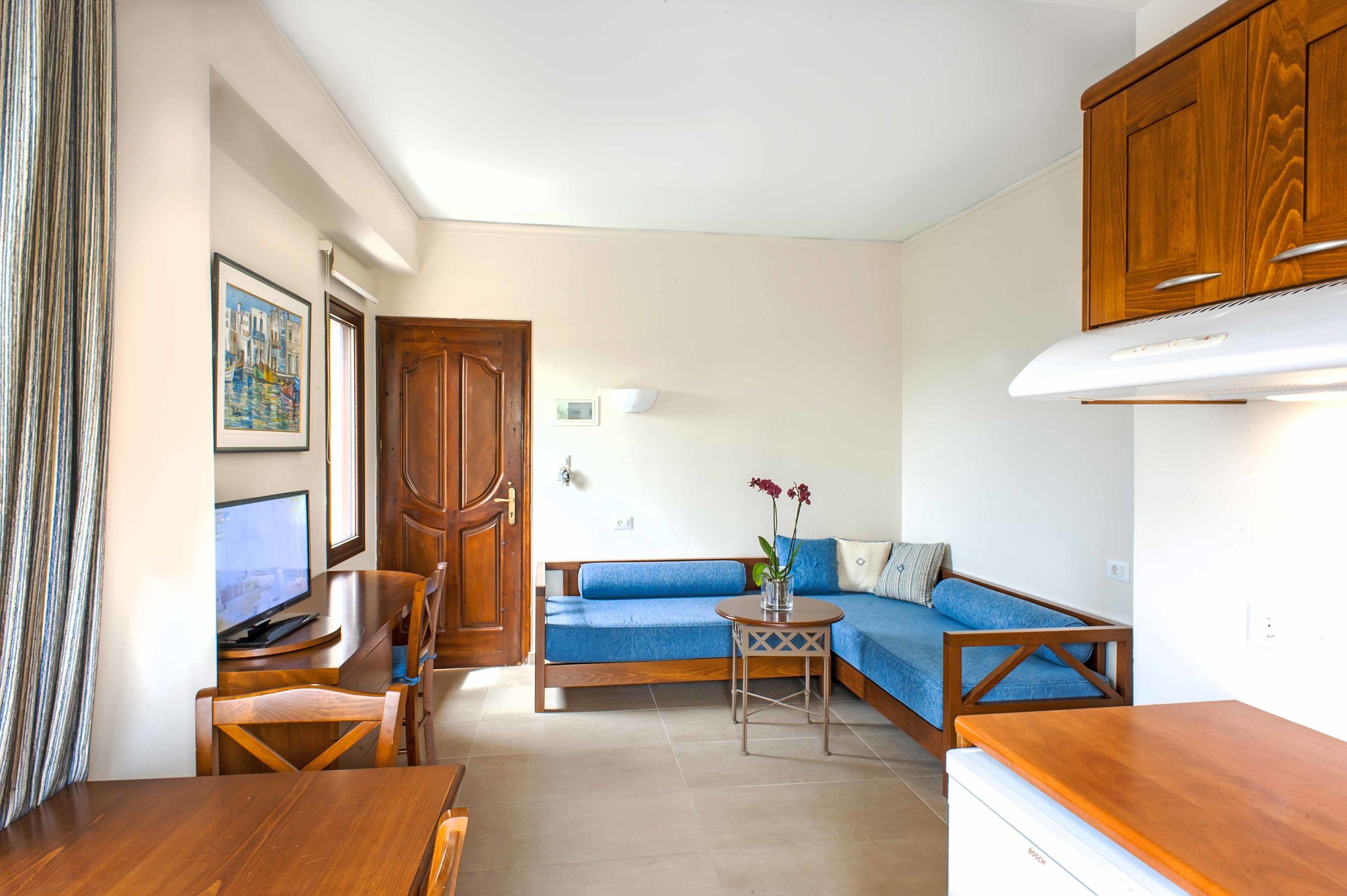 Un espacio habitable compacto con una mesa de comedor de madera, un sofá, una mesita auxiliar y una zona de kitchenette.