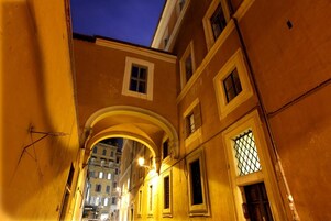 Un estrecho callejón flanqueado por edificios, con puertas y ventanas de arco.