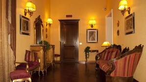 A hallway with a wooden floor, a door at the end, and two upholstered chairs with striped upholstery. - Domus Livia Luxury Suites (Rome)