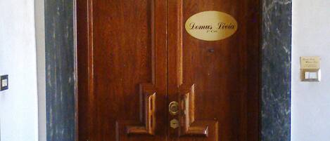 Puerta doble de madera con una placa que reza "Domus Livia" y un marco de mármol.