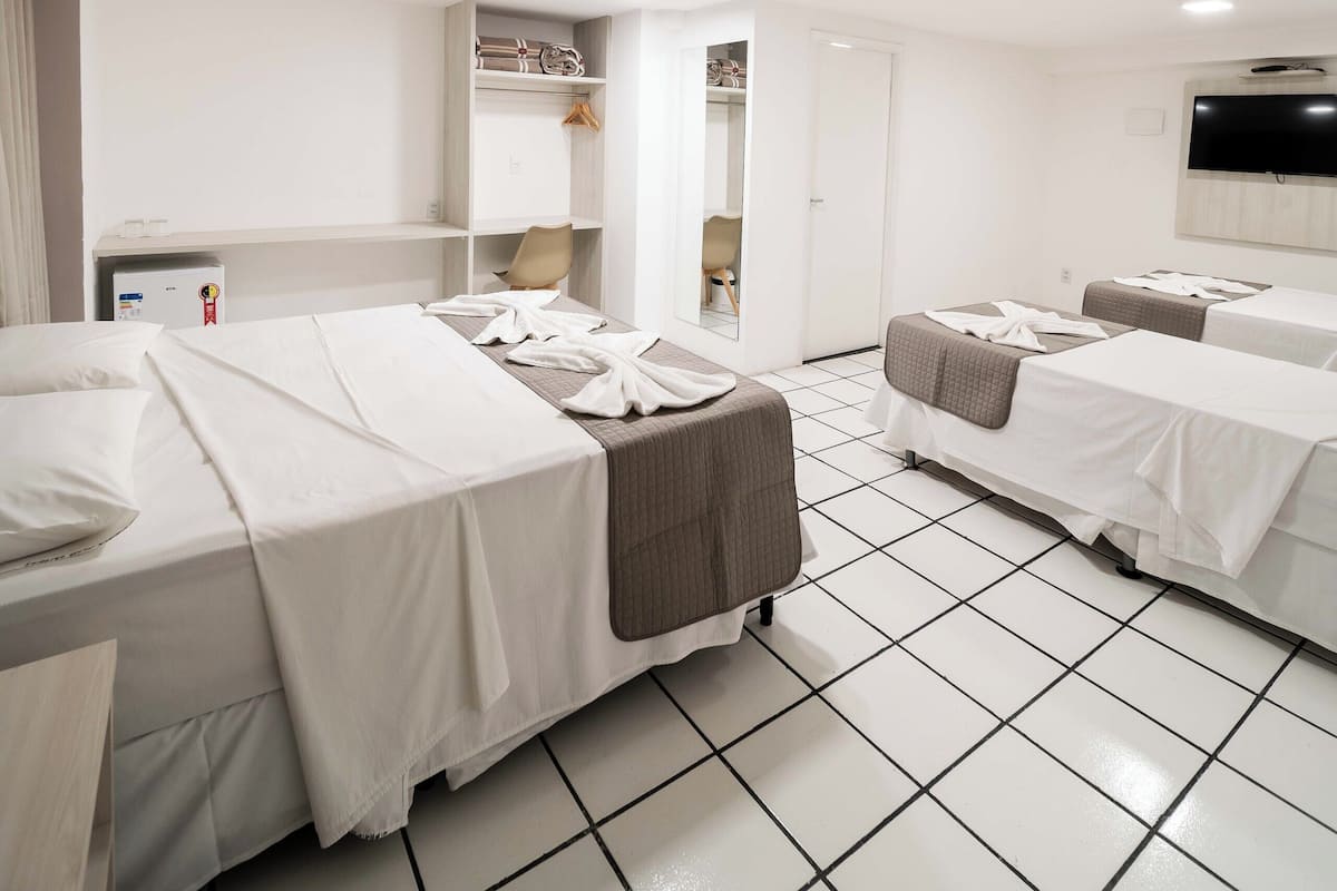 Une chambre d’hôtel avec deux lits, une télévision, un bureau et une armoire.