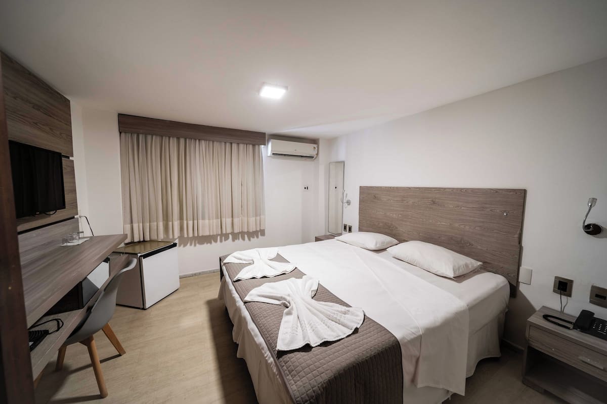 Une chambre d’hôtel comprenant un lit, une table de chevet, un bureau et une chaise.