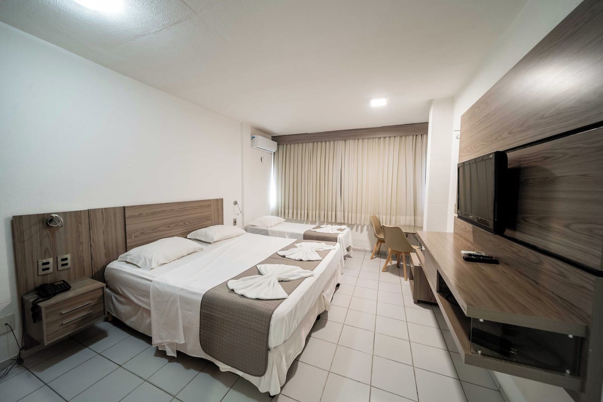 Une chambre d’hôtel avec deux lits, un bureau, une télévision et une chaise.