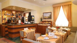 A hotel dining area with a bar, breakfast buffet, and seating arrangements. - Hotel Argentina (Rome)