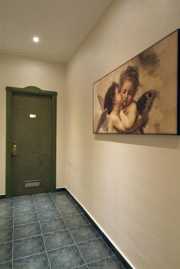 A hallway with a green door and a large painting of cherubs on the wall. - Hotel Argentina (Rome)