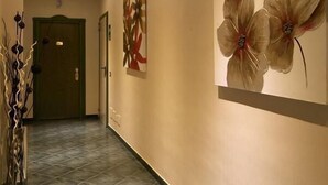 A hallway with a green door at the end, a wall-mounted light fixture, and a decorative plant on the left. - Hotel Argentina (Rome)