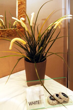 Un baño con una planta en maceta, un estante de vidrio y un letrero que dice "WHITE".
