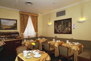 Un comedor con mesas dispuestas para el desayuno, que incluye un bufé y un cuadro en la pared.