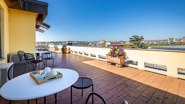 A rooftop terrace with tables and chairs, a flower planter, and a view of the cityscape. - Alla Dimora Altea (Florence)