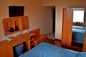 A hotel room with a bed, a wooden desk with a telephone, a mirror, and a wardrobe. - Royal Beach (Varna)