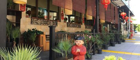 A traditional building with a tiled entrance, potted plants, and a decorative statue.