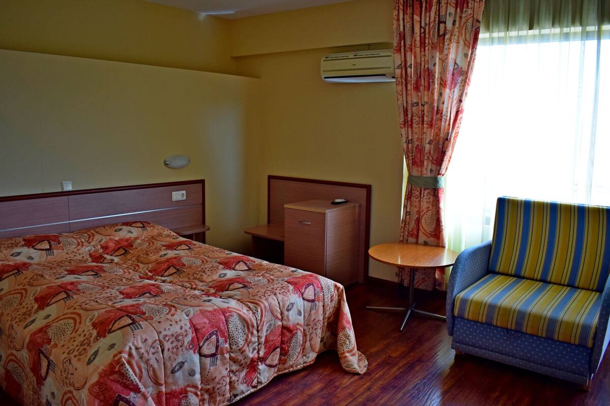Una habitación de hotel con una cama, un escritorio, una silla y un equipo de aire acondicionado.