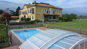 Un edificio amarillo con piscina y terraza acristalada.