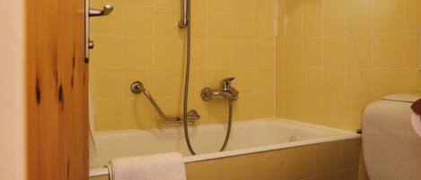 A bathroom with a bathtub, a toilet, and a showerhead.