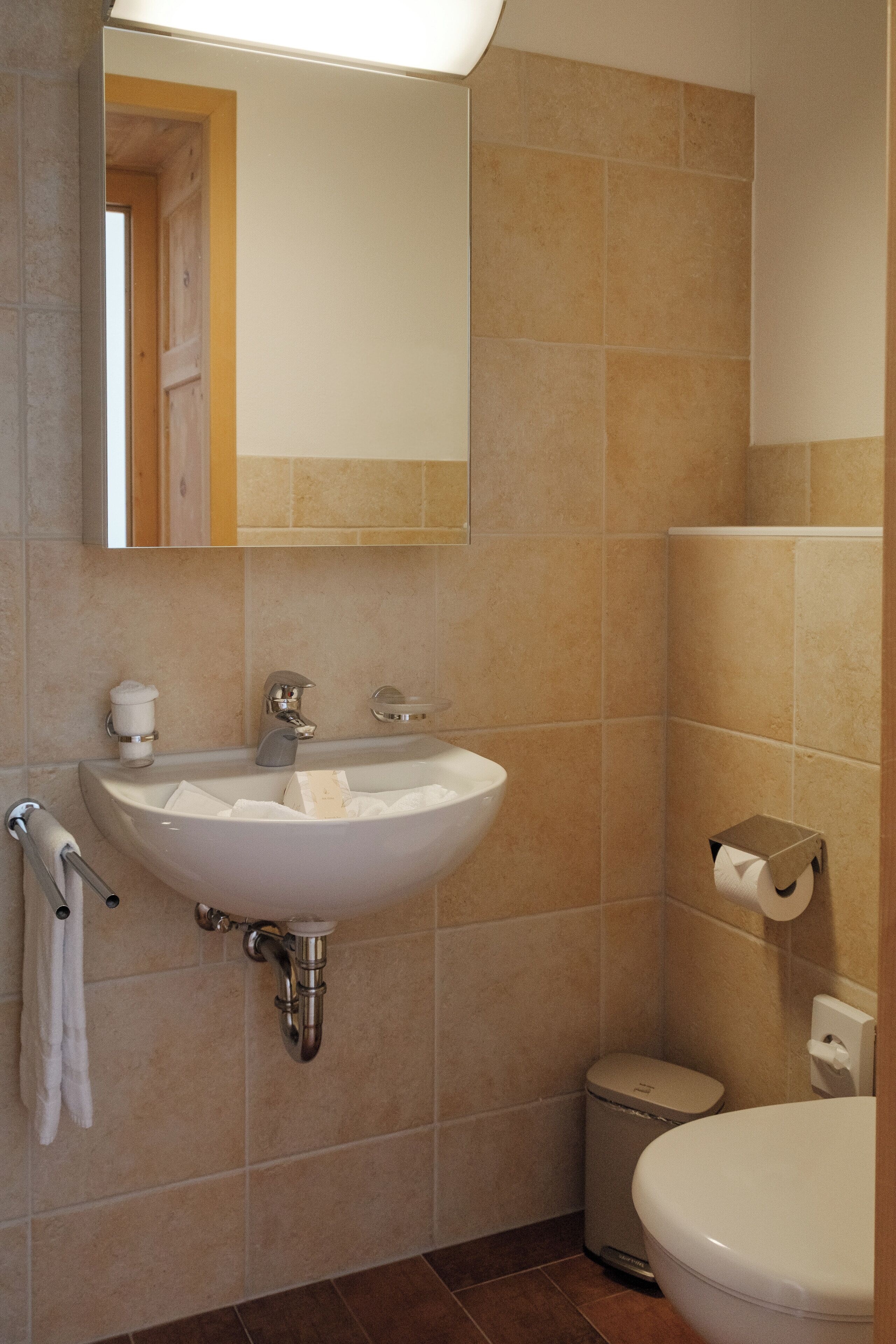 Un baño con lavamanos, espejo y retrete blancos.