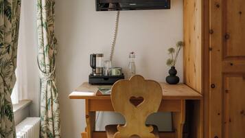 Ein Holztisch mit einem herzförmigen Rücken, ein darüber montierter Fernseher und ein kleiner Blumentopf an der Seite.