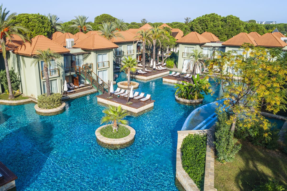 A resort with multiple swimming pools, palm trees, and lounge areas.