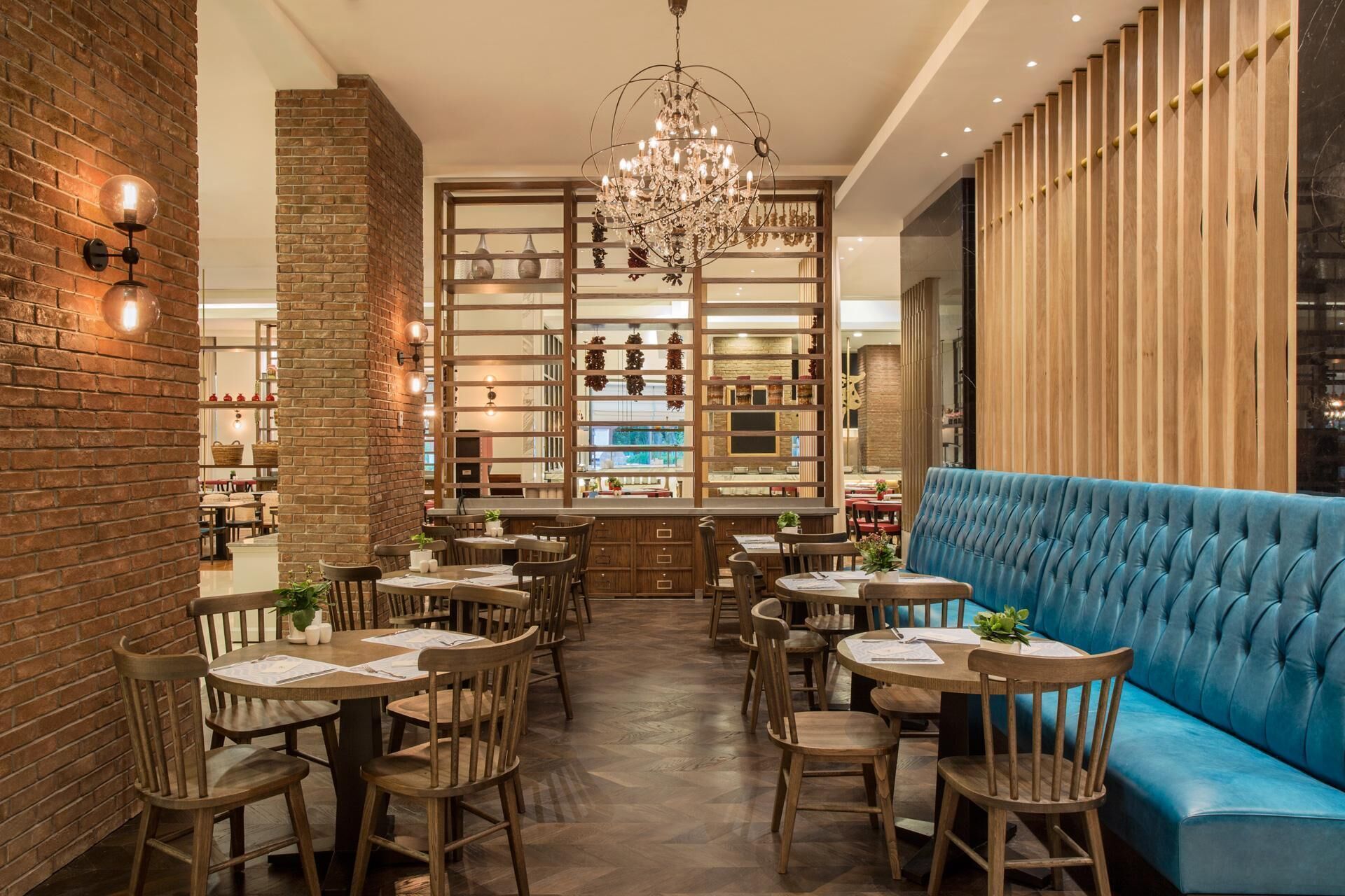A restaurant with brick walls, wooden tables, and a blue upholstered bench.