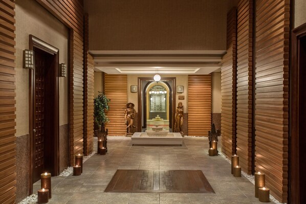 A hallway with wooden paneling, a central fountain, and statues.