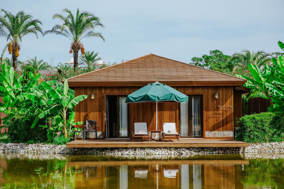 A wooden building with a pool, two lounge chairs, and an umbrella.