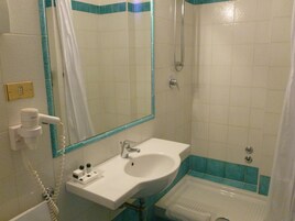 Un baño con lavamanos blanco, un espejo, ducha e inodoro.