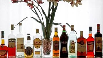 Variedad de botellas de licor dispuestas sobre una mesa, con un jarrón de flores en el centro.