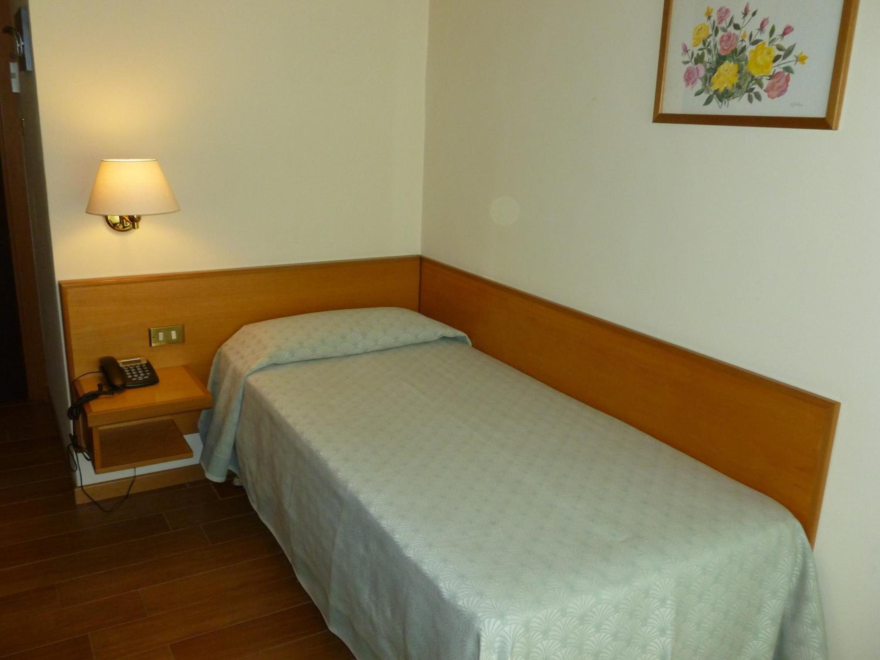Una cama individual con cabecera de madera en una habitación con suelo de madera.
