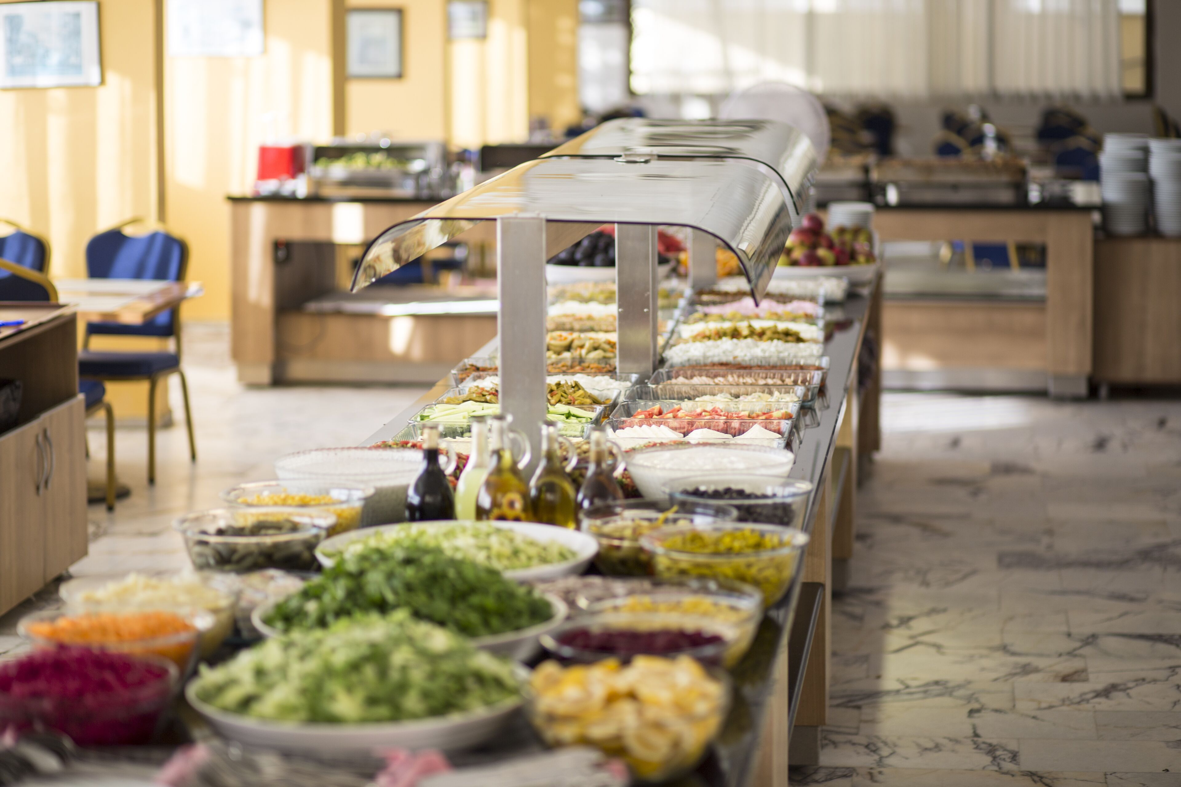 A buffet with various food options, including salads, fruits, and desserts, arranged on a long table.