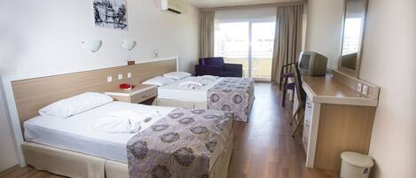 A hotel room with two beds, a desk with a computer, a chair, and a window with curtains.