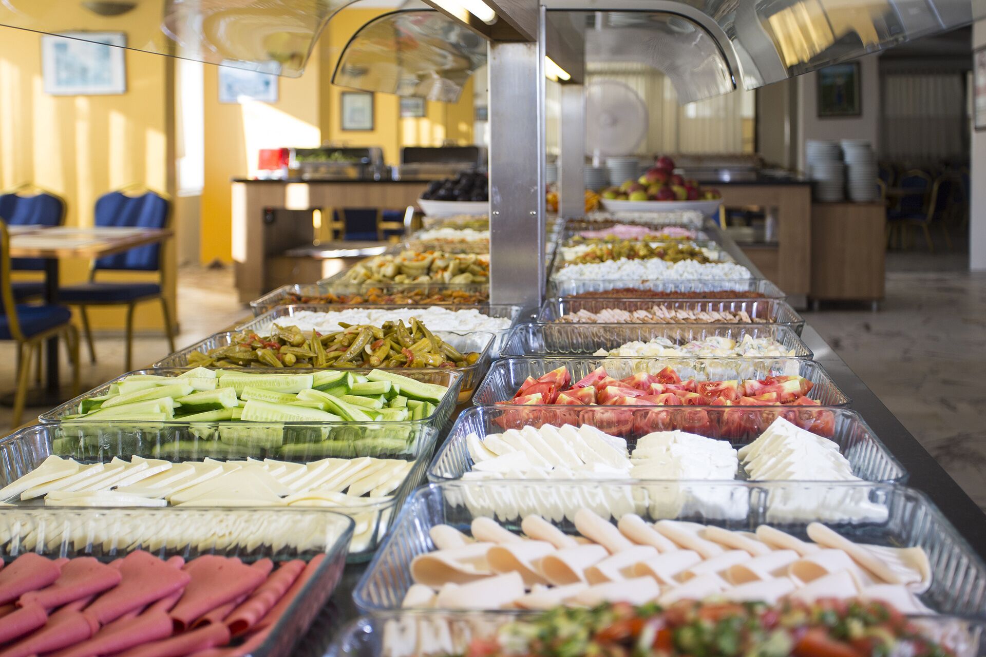 Un bufé con diversas opciones de comida, incluyendo carnes, quesos y verduras.