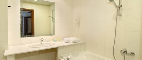 A bathroom with a white sink, a mirror, a bathtub, and a shower.