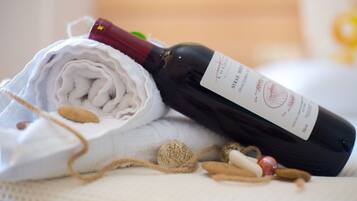 Une bouteille de vin avec une étiquette, une serviette enroulée et quelques éléments naturels, comme des noix et une pelote de ficelle, posés sur une surface texturée.