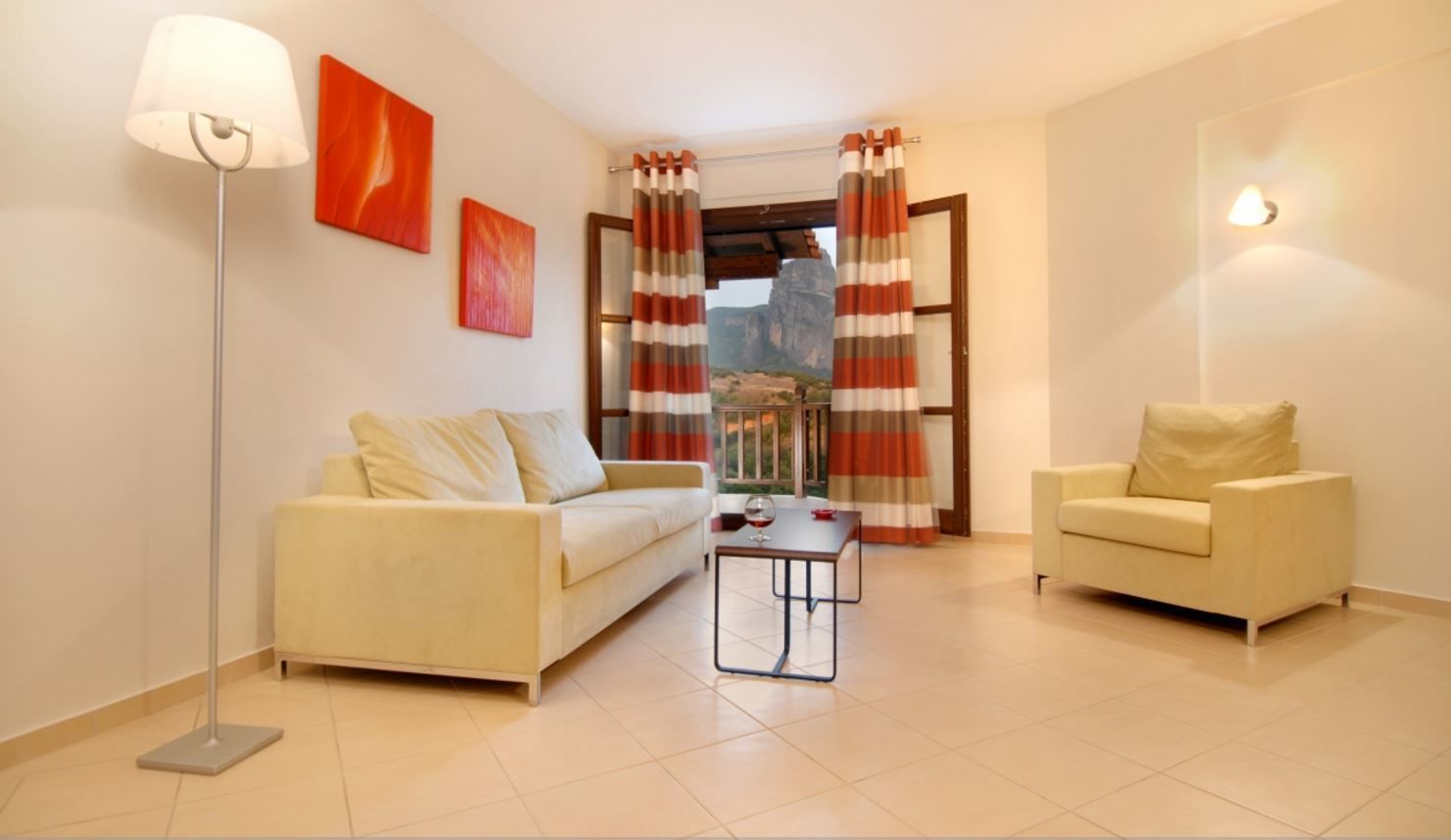 A living room with two sofas, a coffee table, a floor lamp, and a view through a window with curtains.
