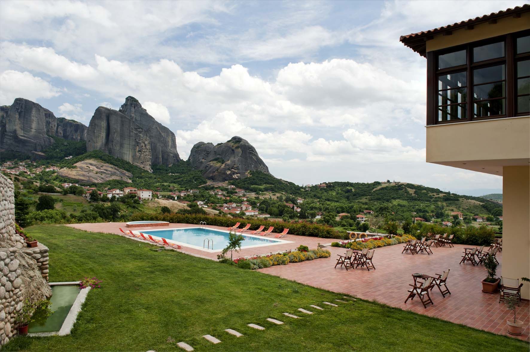 A pool area with lounge chairs, a stone wall, and a view of mountains.