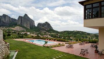 A pool area with lounge chairs, a stone wall, and a view of mountains.