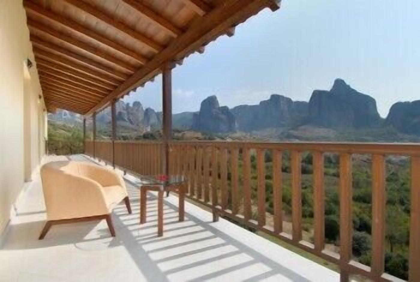 A balcony with a wooden railing overlooking a mountainous landscape.