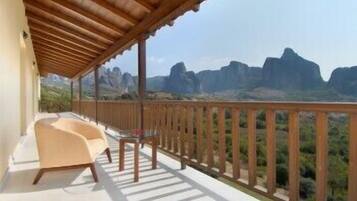 A balcony with a wooden railing overlooking a mountainous landscape.