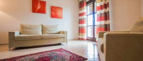 A living room with a beige sofa, a patterned rug, and two abstract paintings on the wall.