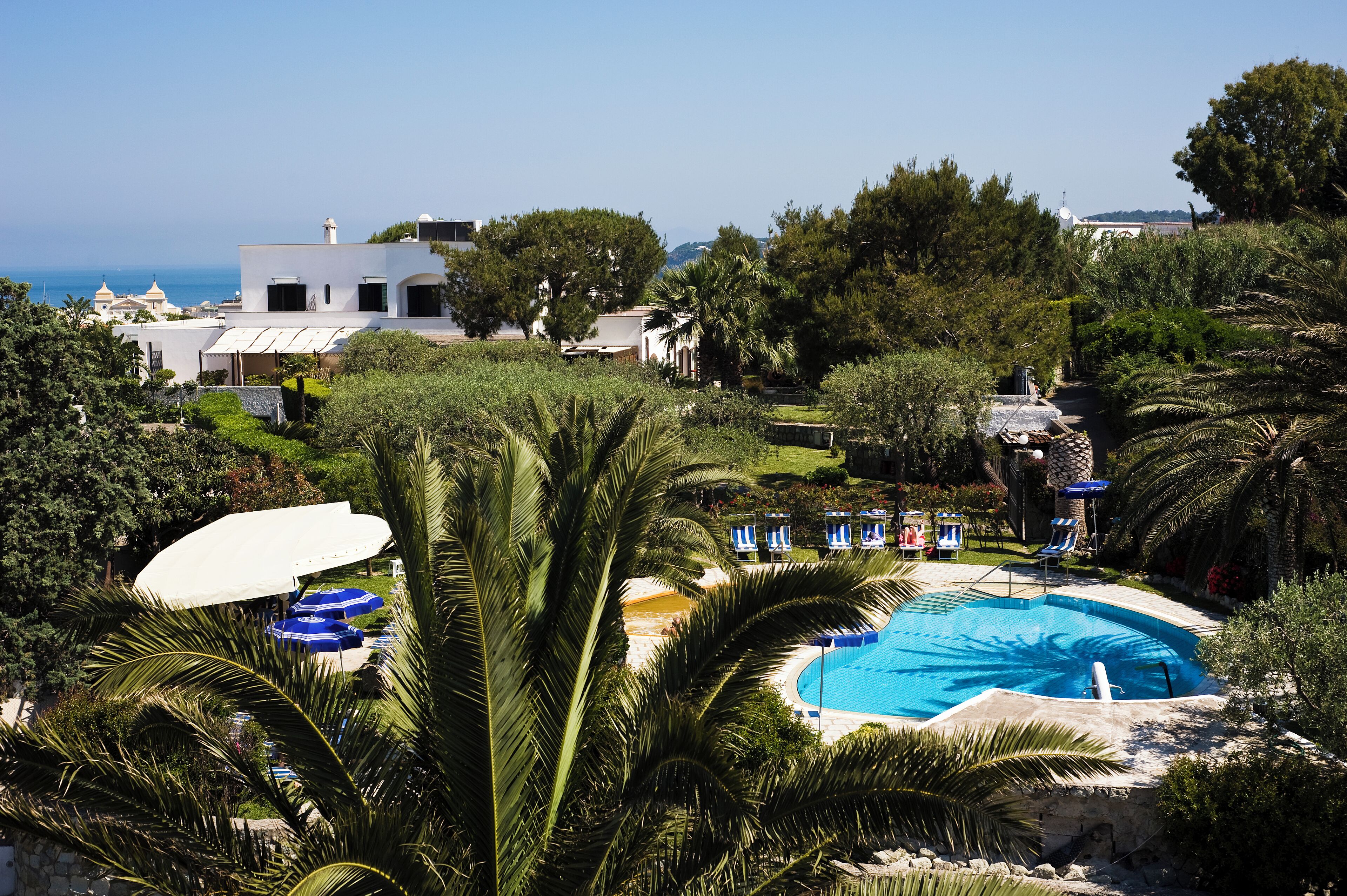 Un resort con piscina, sillas de descanso y vista al mar.