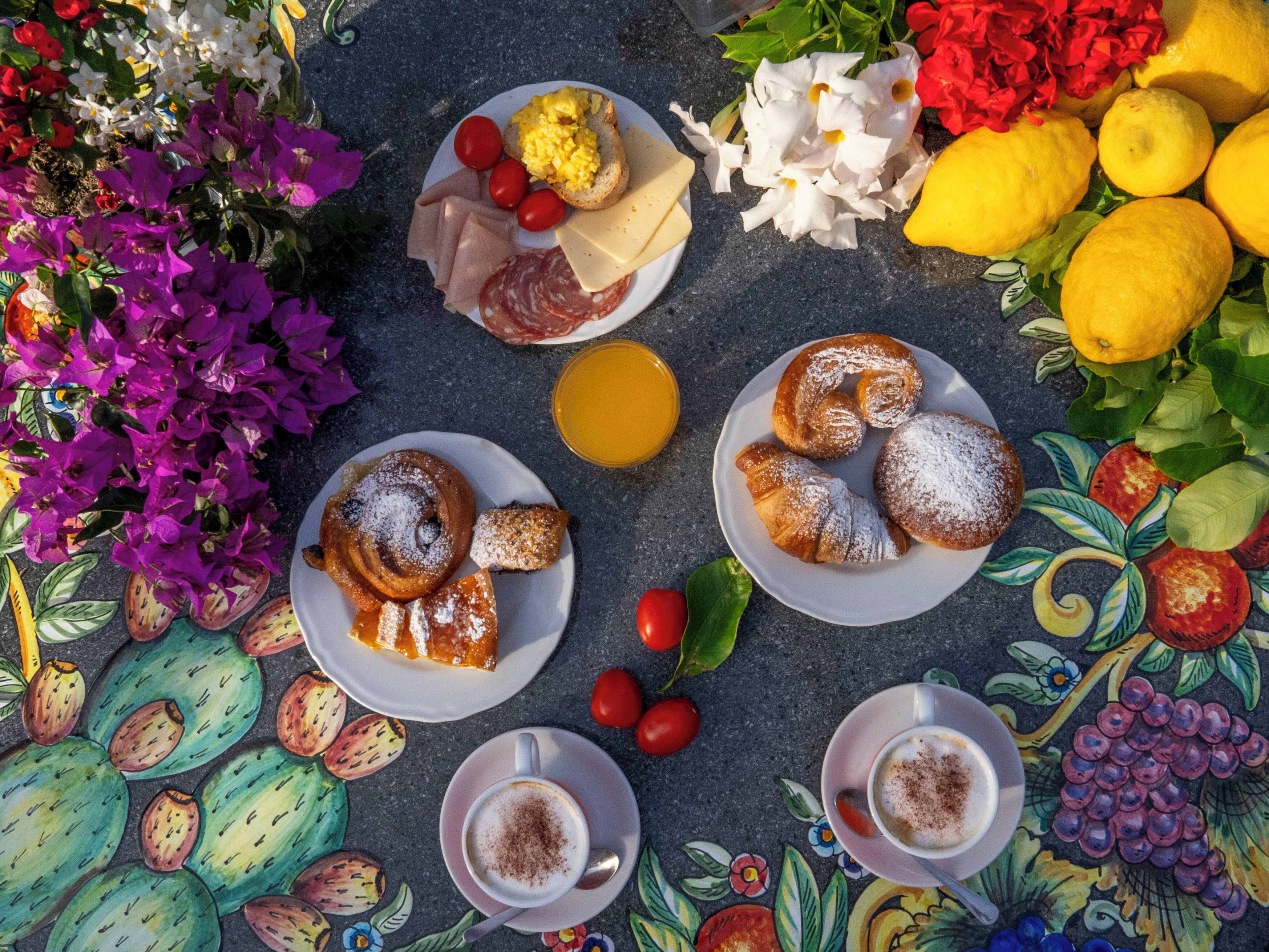 Een tafel met borden eten, kopjes koffie en een verscheidenheid aan bloemen.