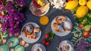 Een tafel met borden eten, kopjes koffie en een verscheidenheid aan bloemen.